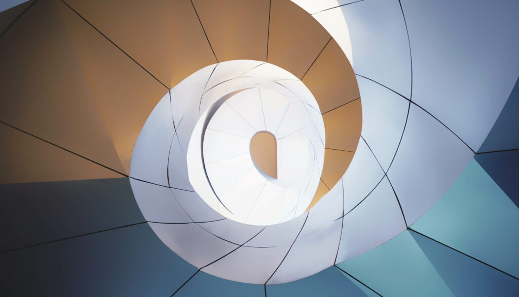 A spiraling glass facade viewed from below with highlights of blue and gold.