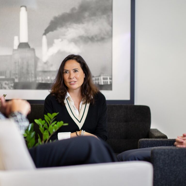 Woman engaged in conversation in a sofa space in an office.
