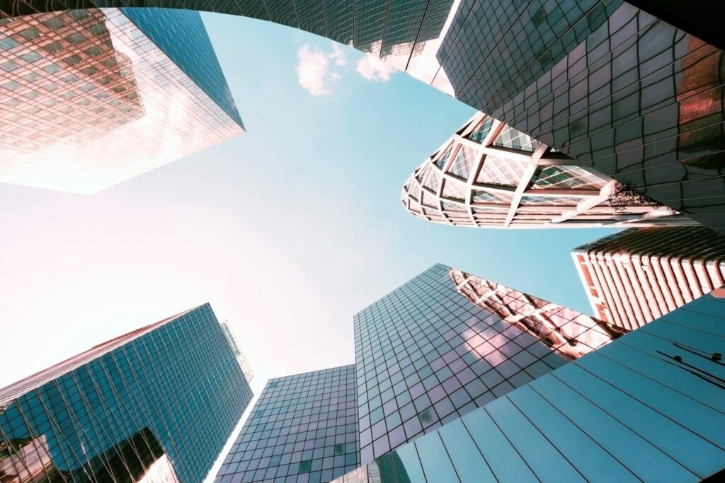 Upward view of modern skyscrapers with glass facades against a blue sky.