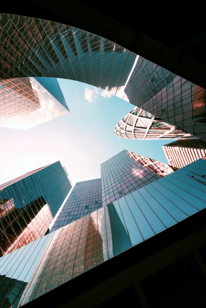 Upward view of modern skyscrapers with glass facades against a blue sky.